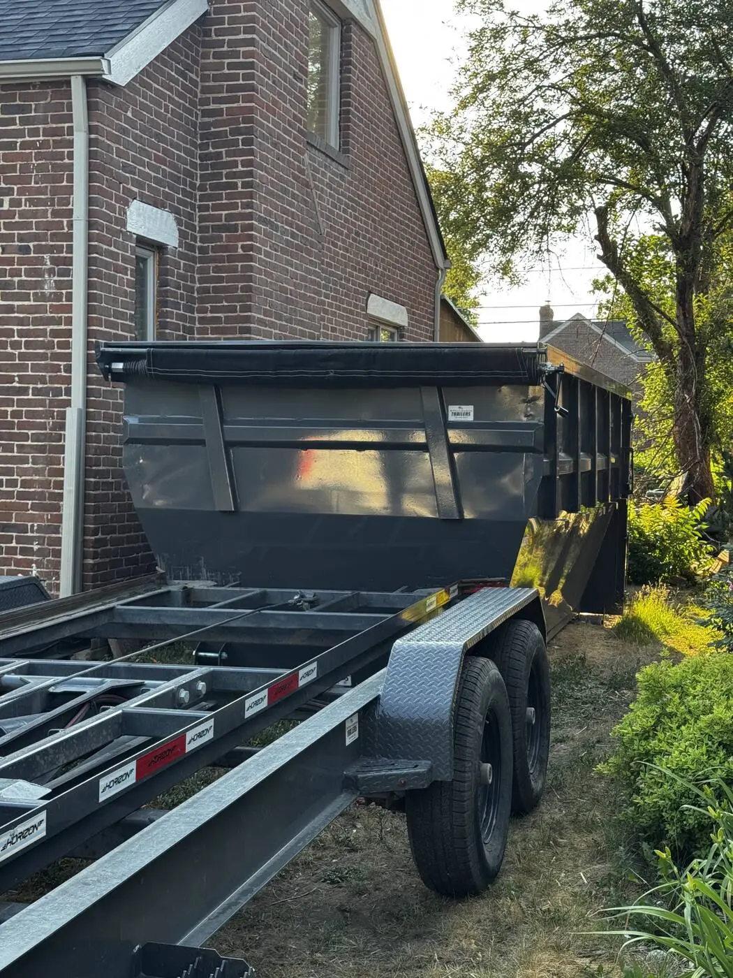 Roll-off dumpster and trailer parked in a Denver driveway